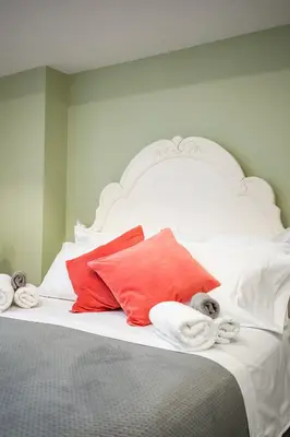 a white bed with red and white pillows on it at Gabby's Place Downtown Core in Toronto