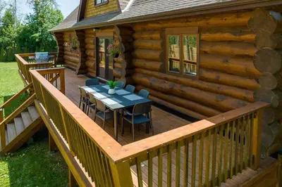 a wooden deck with a table and chairs on a cabin at Unique Log House by the Lake, Retreat with Spa Amenities near Presque'ile Provincial Park in Brighton