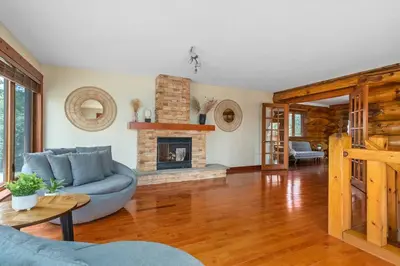a living room with a blue couch and a fireplace at Unique Log House by the Lake, Retreat with Spa Amenities near Presque'ile Provincial Park in Brighton