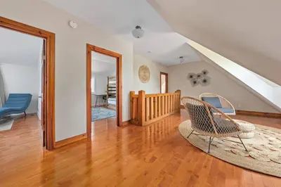 a living room with a chair and a staircase at Unique Log House by the Lake, Retreat with Spa Amenities near Presque'ile Provincial Park in Brighton