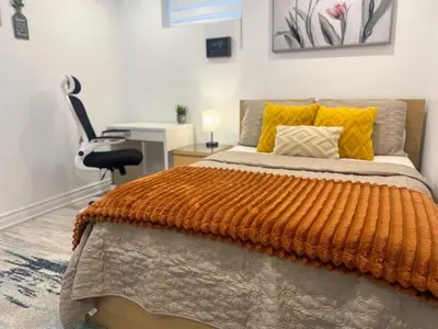 a bedroom with a bed with an orange blanket and a desk at The Khan Villa in Whitby