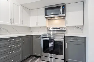 a kitchen with stainless steel appliances and white cabinets at Luxe Lodges on Lake Erie in Port Dover