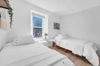 a white room with two beds and a window at Harbour House in Hamilton