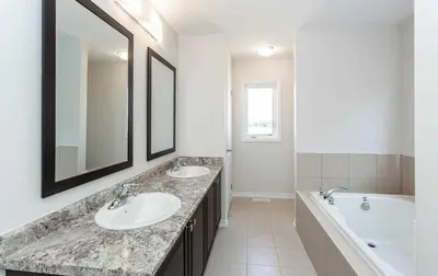 a bathroom with two sinks and a tub and a mirror at The Warm Welcome Suite in Thorold
