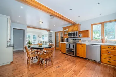 a kitchen with wooden cabinets and a table and chairs at Marmora Retreat - Unique Waterfront Farmhouse in Marmora