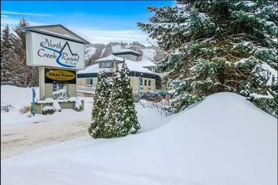 a snow covered street with a hotel and a sign at Slope-side Studio Bliss Ski-in Ski-out, Renovated At Blue, Hot Tub, Fast Wi-Fi in Blue Mountains