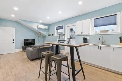 a kitchen with a table and stools in a room at Bright and Spacious Condo in Downtown Collingwood 97043 in Collingwood