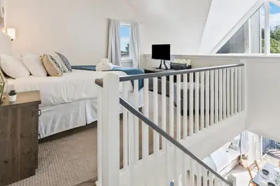 a white bedroom with a bed and a staircase at Blue Mountain The Parker Slopeside in Blue Mountains