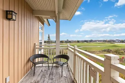 two chairs on a porch with a view of a golf course at Spectacular Rivergrass Chalet Steps to Blue Mtn in Blue Mountains