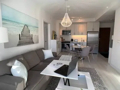 a living room with a couch and a laptop on a table at Stunning Stayz Luxury 2 King Suite at Friday Harbour Resort Marina Walk & Parking in Innisfil