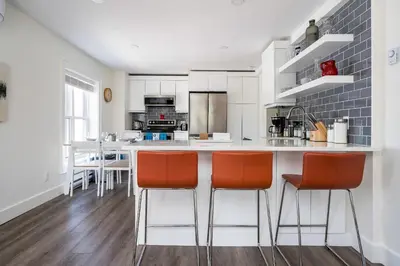 a kitchen with white cabinets and orange bar stools at 