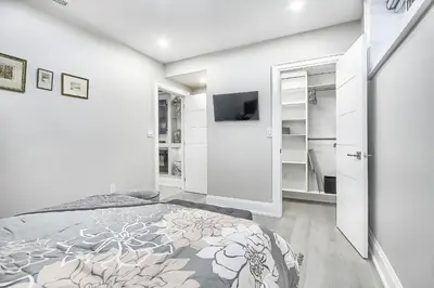 a white bedroom with a bed and a tv at Charming and Luxurious 2BR+1Bath Guest Suite in Toronto
