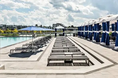 a row of tables and umbrellas next to a pool at PET FRIENDLY CONDOS at FRIDAY HARBOUR in Innisfil