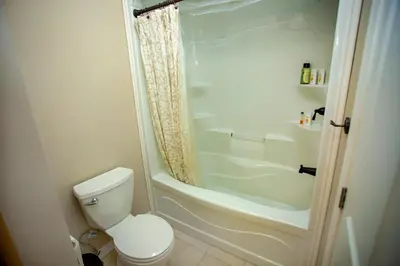 a white bathroom with a toilet and a shower at Mountain House in the Heart of Haliburton, Mins to Lake in Haliburton