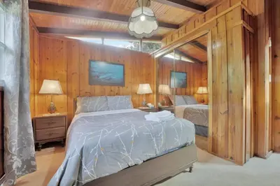 a bedroom with a bed and two lamps and wooden walls at Rustic cottage on Canal Lake in Carden