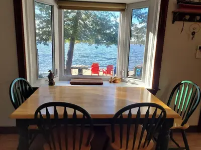 a dining room table with chairs and a view of the water at Rustic Pines Waterfront Cottage *CLEAR WATER* in Fenelon Falls