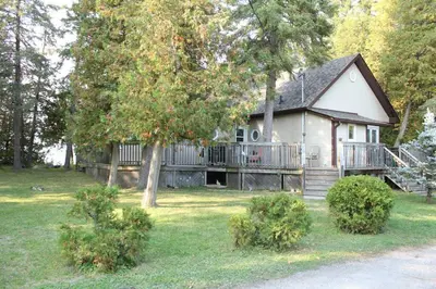 a small house with a porch and a deck at Rustic Pines Waterfront Cottage *CLEAR WATER* in Fenelon Falls