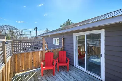 two red chairs on the deck of a house at Muskoka Honey Harbour 4-Bed Retreat with Hot Tub in Honey Harbor