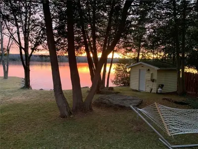 a small shed sitting next to a body of water at Cozy Escape, Kawarthas Cottage With Sauna in Buckhorn