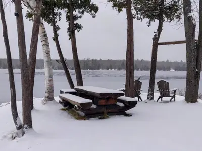 a picnic table covered in snow next to a lake at Cozy Escape, Kawarthas Cottage With Sauna in Buckhorn