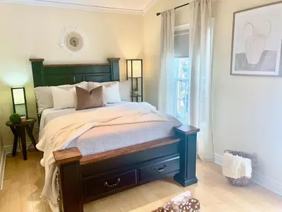 a bedroom with a bed with a green headboard and a window at Suites On King in Niagara on the Lake