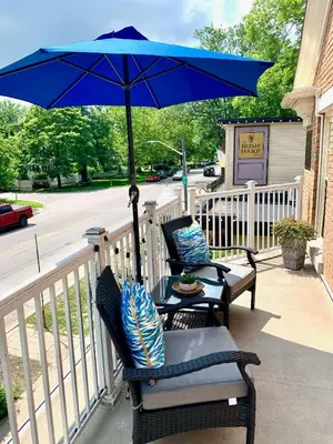 two chairs and a blue umbrella on a porch at Suites On King in Niagara on the Lake
