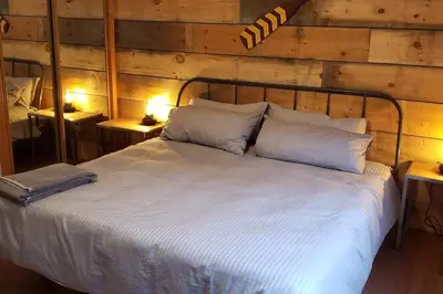 a bedroom with a white bed with two tables at Modern Chic Cottage - Hot Tub, Sauna, Tay Trail in Waubaushene