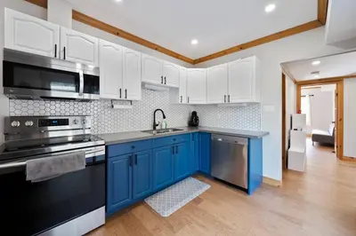 a kitchen with blue cabinets and a sink at Modern Chic Cottage - Hot Tub, Sauna, Tay Trail in Waubaushene