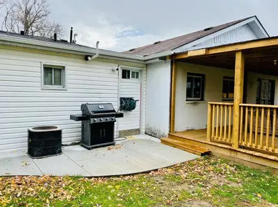 a house with a grill sitting on a porch at 5 Bedroom Vacation Cottage - King City in Schomberg