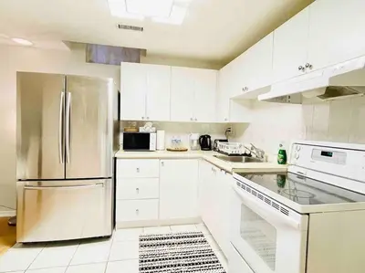 a kitchen with white cabinets and a stainless steel refrigerator at Comfortable Apartment in Richmond Hill in Richmond Hill