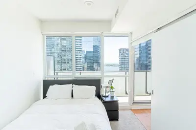 a bedroom with a white bed and large windows at Beautiful Modern Toronto Luxurious Scotiabank Arena in Toronto