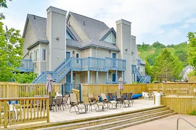 a large house with a deck with chairs and tables at Condo 208 At North Creek Resort in Blue Mountains