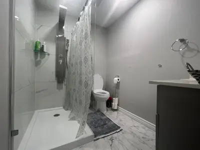 a white bathroom with a shower and a toilet at The Hestia Kitchener in Kitchener