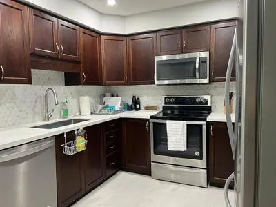 a kitchen with wooden cabinets and stainless steel appliances at The Hestia Kitchener in Kitchener