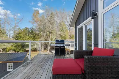 a deck with a couch and a grill on a house at Impressive Modern Waterfront Home on Georgian Bay in Port McNicoll