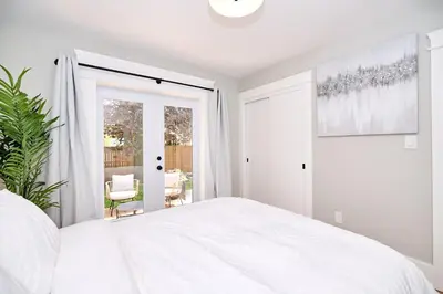 a white bedroom with a bed and a sliding glass door at The Newark House in Niagara on the Lake