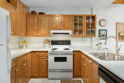 a kitchen with wooden cabinets and a white stove top oven at Bear Essentials Hideaway in Huntsville