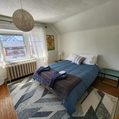 a bedroom with a bed with a blue blanket and a window at The Pandora Century Home in Kitchener
