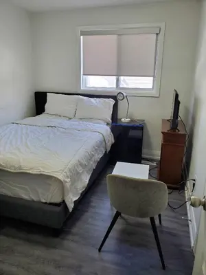 a bedroom with a bed and a chair and a window at Maxwell Esabu in Toronto