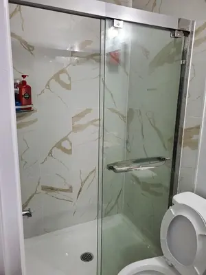 a shower with a glass door next to a toilet at Maxwell Esabu in Toronto