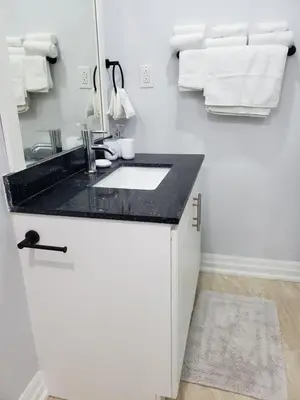 a white bathroom with a sink and a mirror at Luxurious Apt 2BRs-1BA Spacious Modern, with free parking in Brampton