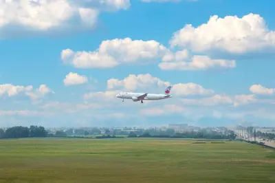 an airplane is flying in the sky over a field at Tru By Hilton Toronto Airport West in Mississauga