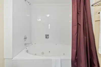 a bath tub in a bathroom with a red shower curtain at Blue Mountain Ski In Ski Out Resort Condo 2 Level in Blue Mountains