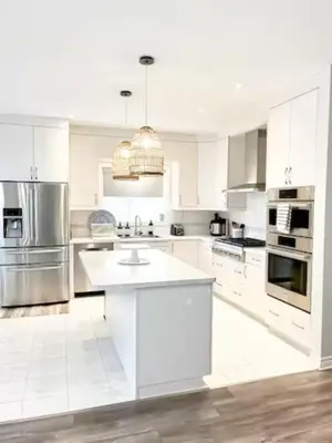 a white kitchen with white cabinets and stainless steel appliances at Inspired Stay close to Niagara *4B & 2King Beds* in Thorold