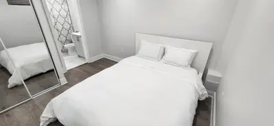 a white bed with two pillows and a mirror at Cozy 2 Bedrooms & 2 Bathrooms Guest Suite with Electric Fireplace in Georgetown