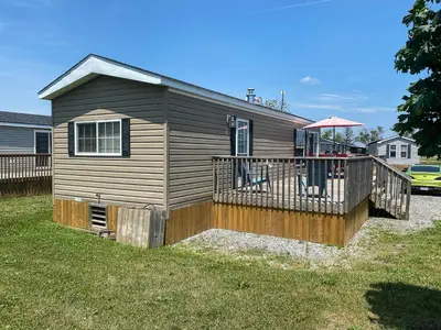 a small house with a deck and an umbrella at Falcon Cottages in Niagara on the Lake